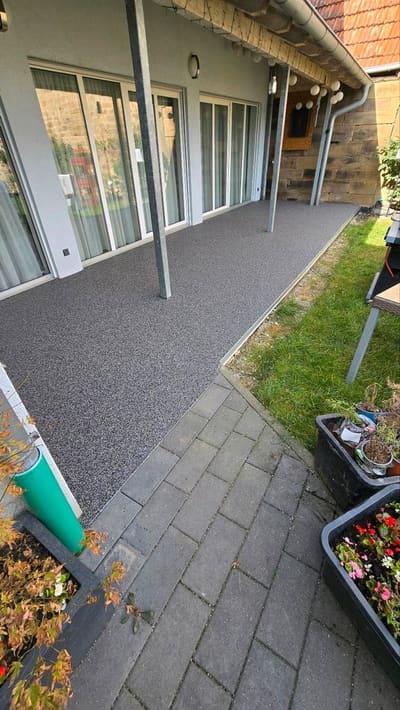 Überdachte Terrasse mit grauem Steinteppich und Blick in den Garten – Terrassensanierung von mf.steintechnik aus Kirchheim am Neckar