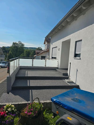 Terrasse in Hanglage mit Steinteppich und Geländer – Terrassenbau von mf.steintechnik aus Kirchheim am Neckar