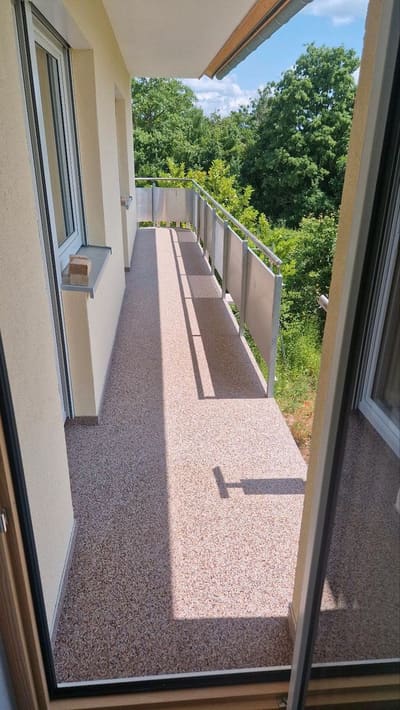 Langer Balkon mit rötlichem Steinteppich entlang der Fassade – Balkonsanierung von mf.steintechnik aus Kirchheim am Neckar