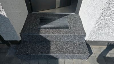Eingangsbereich mit Steinteppich und eingelassenem Entwässerungsgitter – Abdichtung und Belag von mf.steintechnik aus Kirchheim am Neckar